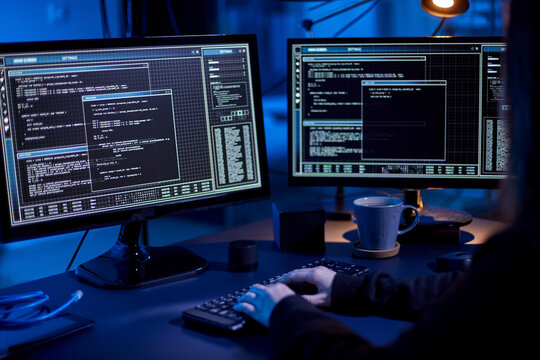cybercrime, hacking and technology concept - close up of female hacker in dark room writing code or using computer virus program for cyber attack