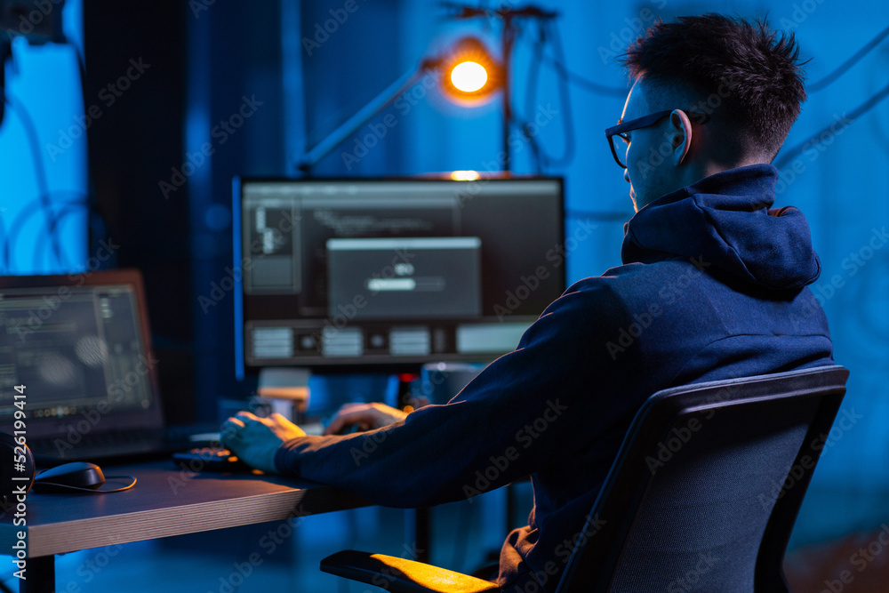 Poster cybercrime, hacking and technology concept - male hacker in dark room writing code or using computer