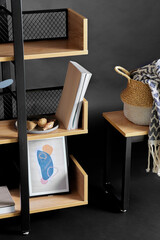 interior and home decor concept - book shelf with art and decorations over black background