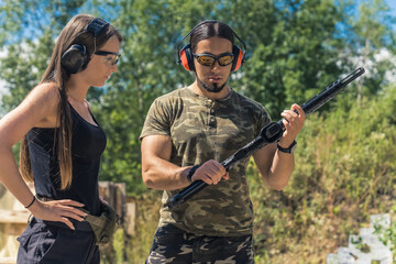 Shooting with a gun or a rifle as a sport and hobby. Caucasian male instructor in moro t-shirt...