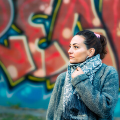 Portrait of an adult caucasian woman looking to a vanishing point outdoors with a painted wall as background