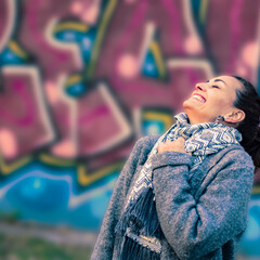 Portrait of an adult caucasian woman laughing out loud outdoors with a painted wall as background
