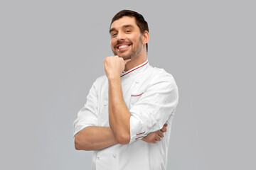 cooking, culinary and people concept - happy smiling male chef in jacket over grey background