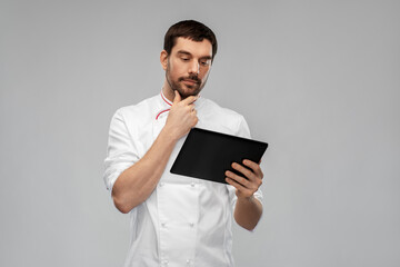 cooking, culinary and people concept - thinking male chef with tablet pc computer over grey background