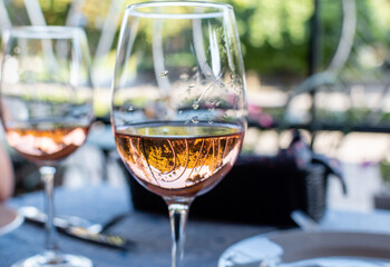 Rose wine in wine glass close-up with reflections on blurred background of summer cafe