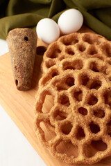 Fritters placed on a wooden base and around a panela and two eggs.