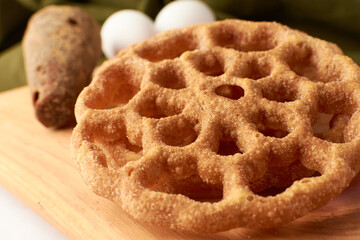Fritters placed on a wooden base and around a panela and two eggs.