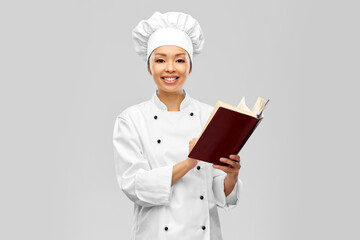 cooking, culinary and people concept - happy smiling female chef reading cook book over white background