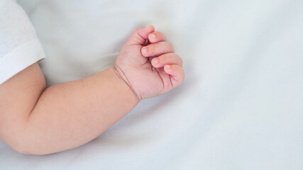 Hand of little baby on white sheet bed background. Cute boy and chubby hands