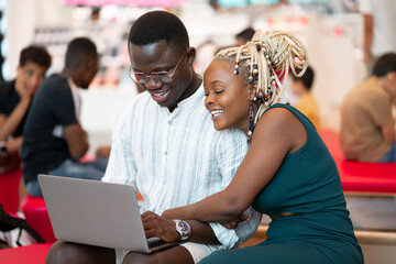 Fototapeta na wymiar Giovani amanti africani che trascorrono del tempo al bar a guardare i media insieme sul laptop