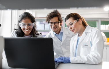 science research, work and people concept - happy international team of scientists with laptop...