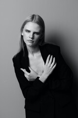 Blonde in a suit hugs herself while putting on a jacket