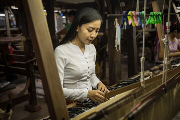 local Amarapura woman weaving hand-made tradional myanmar fabric at weaving factoryin Mandalay Myanmar