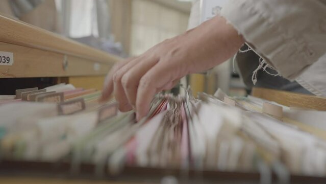 Hands of a business man searching for documents in a filing cabinet at the office.