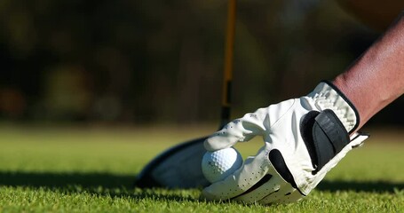 Male golfer hand placing golf ball on the tee at golf course, closeup