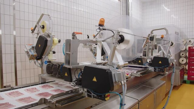 Machine for sticking labels on packaging. Thinly sliced bacon being prepared for shipping to retailers