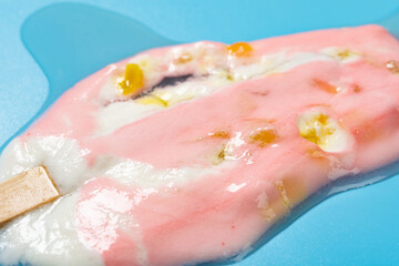 angle view peach flavor popsicle melted on blue background close up