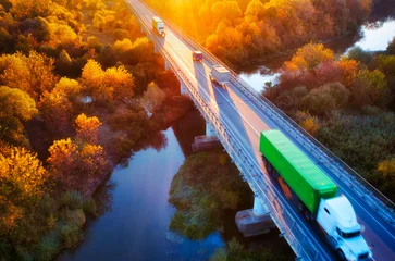 Wall murals North Europe The truck is driving across the bridge over the river Drone view of the autumn forest.