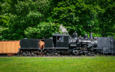 A View of a Antique Shay Steam Engine Warming Up Blowing Steam on a Sunny Day