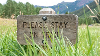 The Please Stay on Trail sign in grass