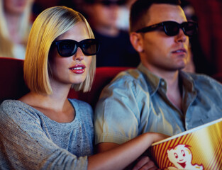 Obraz premium Couple, 3D movie and cinema of a man and woman sitting and eating popcorn together wearing glasses. People in a relationship watching a film in a theatre for indoor entertainment while having snacks.