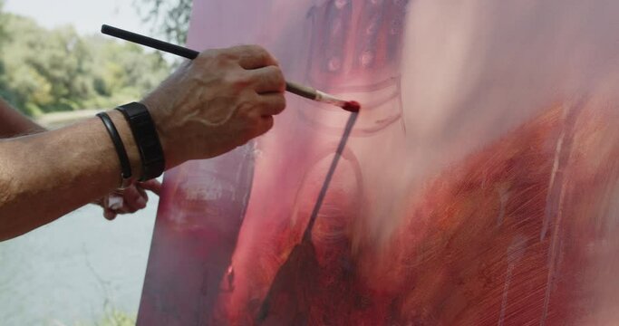 An artist painting church exterior with oil colors on canvas, outdoor scene, hand close-up shot.
