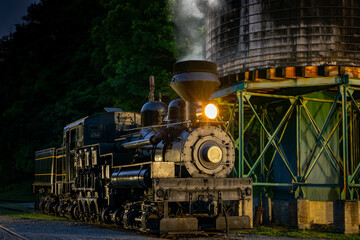 A Dusk Shot of a Antique Shay Steam Engine, Warming Up at a Water Tower, on a Summer Evening