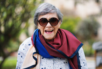 Portrait of happy old woman laughing wearing sunglasses