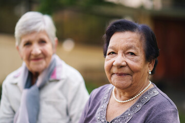 Obraz premium Two elderly women sitting on bench in park smiling happy life long friends enjoying retirement