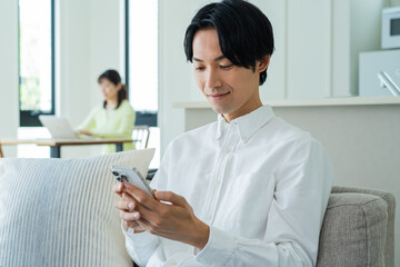 自宅で携帯を触る日本人男性