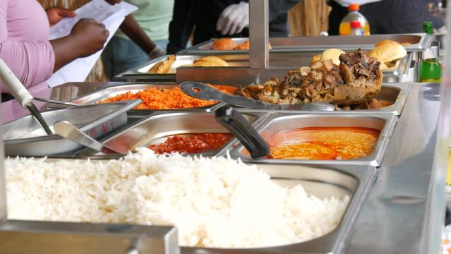 Showcase with traditional African food at a street food festival. Meat, rice, carrots, various sauces and pastries