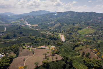 View from a drone of a landscape with crops and a highway between mountains in the background