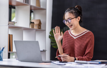 Young attractive Freelancer business asian woman talking about sale report in video call conference on laptop computer online meeting in the workplace, finance Work remotely Social isolation concept.