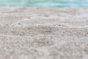 Fototapeta na wymiar Beach sand blue sea water summer background with shallow depth of field.
