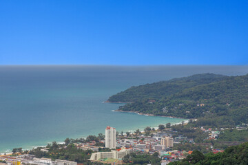 Fototapeta premium Karon Beach in Phuket Thailand, turquoise blue waters, lush green mountains colourful skies. Phuket is a tropical island many palms