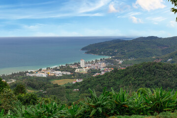 Obraz premium Karon Beach in Phuket Thailand, turquoise blue waters, lush green mountains colourful skies. Phuket is a tropical island many palms
