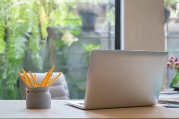 Laptop computer, pencil holder and Supplies on wooden office desk.