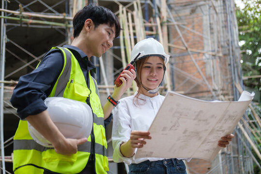 Architect woman and civil engineer man discussing the structure of the building with architects at construction site.