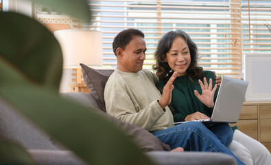 Happy mature mid age couple making video call, chatting with friends via laptop computer.