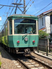 Fototapeta na wymiar Local train from Kamakura to Enoshima in Japan, passing by houses closely 