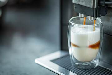 Espresso machine making fresh coffee latte. Shot of espresso being pour into fresh steamed milk