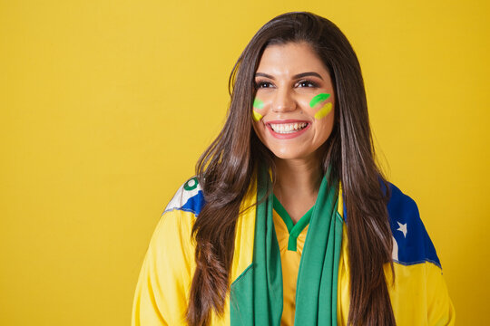 Woman supporter of Brazil, world cup 2022, soccer championship, using brazil flag as cover. close-up photo, smiling, watching football match.