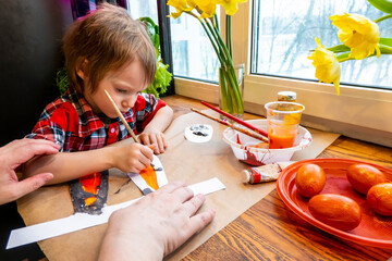 boy draws paper rabbit ears. Preparation for Easter: a child paints paper rabbit ears with paints...