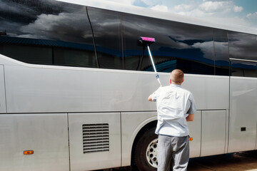 Driver brushes large tinted windows of bus on summer day. Care and maintenance of equipment....