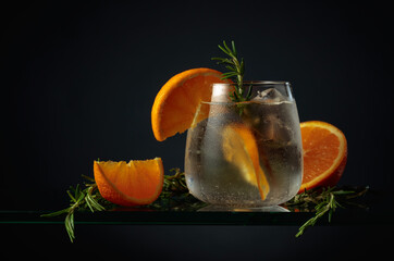 Cocktail with ice, orange, and rosemary.