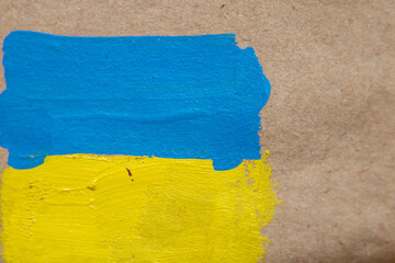 The flag of Ukraine is painted with paints on brown paper