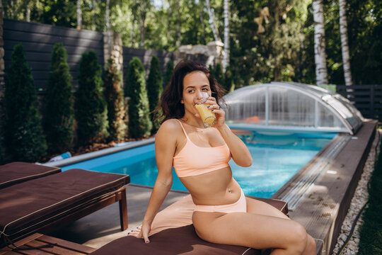 portrait of woman hand enjoy holiday vacation with orange juice in swimming pool (this image for outdoor and relaxation concept)