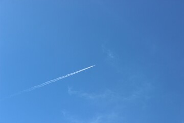 Airplane flying in the blue sky leaving contrails from behind - obrazy, fototapety, plakaty