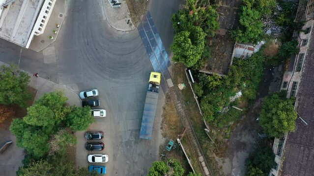 Aerial view from above of grain lorry or dump truck driving through the industrial area of grain elevator silos. Top view of emty body trailer driving along the road. Air drone copter footage.