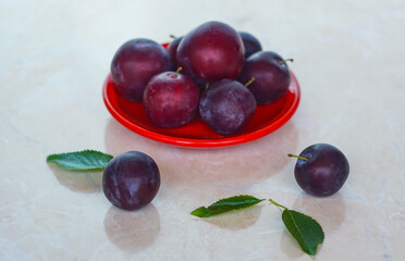 Plums in a red bowl